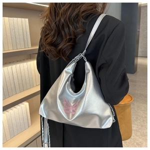 Silver metallic bucket bag with pink butterfly embroidery and chain strap on a model
