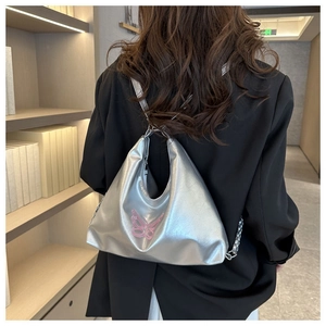 Detail of silver metallic backpack with pink butterfly design and stylish chain straps