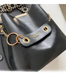 Detailed close-up of a black bucket bag featuring golden hardware and woven shoulder strap