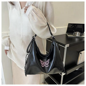 Detail showing shiny black faux leather hobo bag with pink butterfly embroidery and chain