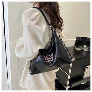 Detail of black glossy leather hobo bag with pink butterfly embroidery and chain strap
