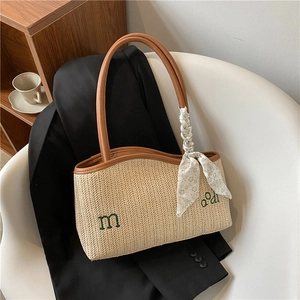 Large beige woven straw tote bag with brown leather handles and green letter embroidery