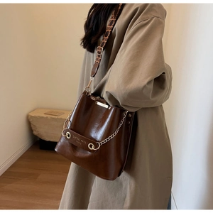 Dark brown leather bucket bag shown with bohemian strap and metallic chain detail