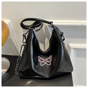 Detail of black hobo bag featuring pink butterfly embroidery and silver chain strap