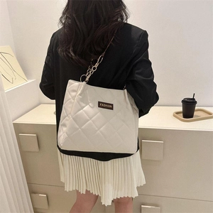 Quilted cream tote bag with gold chain strap and diamond pattern in modern interior