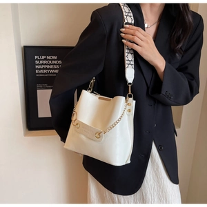Detail view of cream leather bucket bag with gold chain and patterned strap