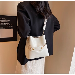 Detail of off-white bucket bag with golden chain and geometric pattern woven strap