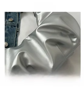 Nahaufnahme der silbernen Ledertasche mit Falten, Denim-Stoff und Metallknöpfen