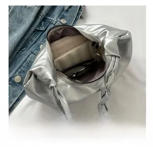 Silberne Metallic-Cloud-Bag zeigt Innenkapazität mit Sonnenbrille und Handy im Inneren