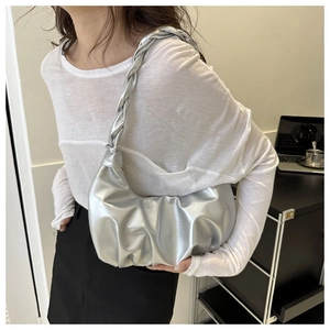 Nahaufnahme der silbernen Plissee-Tasche mit geflochtenem Griff an der Schulter eines Models