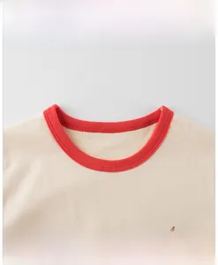 Détail de l'encolure du t-shirt blanc cassé avec bord rouge et imprimé Enjoy