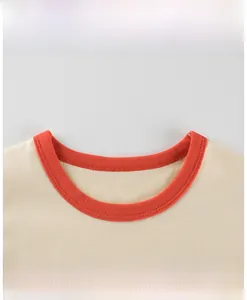 Close-up detail of the contrast orange ribbed neckline on the beige long-sleeved baby t-shirt