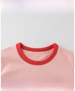 Detailed macro view of the contrasting red ribbed neckline on a pink cotton t-shirt