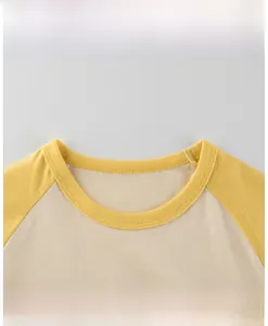 Détail d'un t-shirt raglan bébé avec col rond jaune côtelé et coutures soignées