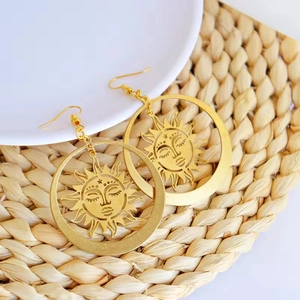 Bohemian gold sun goddess hoop earrings with intricate hollow face design on white tray