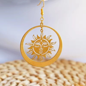 Detail of bohemian sun goddess earrings featuring sun deity face and vintage gold finish