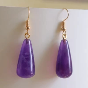 Gros plan détaillé des boucles d'oreilles en améthyste en forme de goutte d'eau dorées
