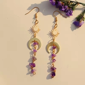 Golden sun and moon earrings with amethyst stones and purple tassels in natural sunlight