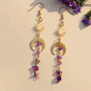 Bohemian gold sun and moon earrings with purple amethyst tassel drops on beige background