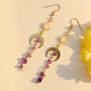 Macro detail of gold sun and moon earrings with purple amethyst stone tassels