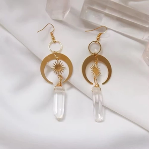 Golden sun and moon drop earrings with clear crystal quartz prisms on silk background