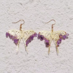 Detailed macro of gold butterfly earrings with crushed amethyst crystals and hooks