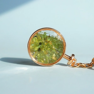 Dettaglio del ciondolo circolare dorato riempito con pietre di cristallo di peridoto