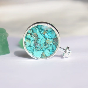 Macro-opname van zilveren hanger met natuurlijke turquoise schilfers en schroefsluiting