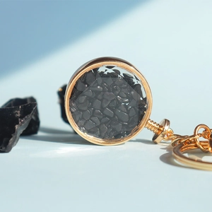 Dettaglio del portachiavi dorato con frammenti di cristallo nero e pietra minerale grezza