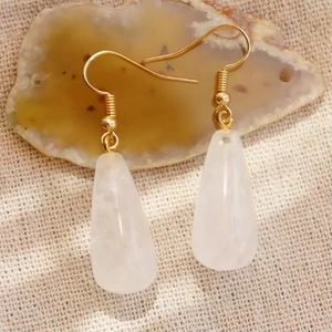 Élégantes boucles d'oreilles dorées avec gouttes en pierre de lune sur fond naturel