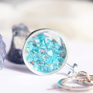 Macro-detail van de ronde zilveren sleutelhanger met facetgeslepen kristal en turquoise