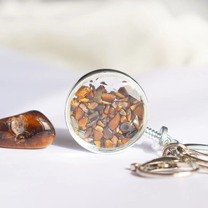 Macro-opname van ronde sleutelhanger met tijgeroog kristallen in glazen behuizing