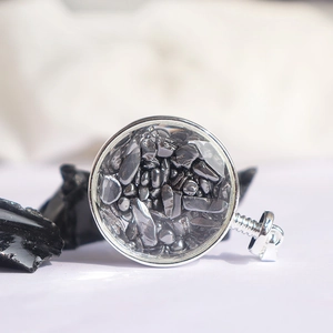 Detailopname van een zilveren ronde hanger gevuld met hematiet op een zwarte rots