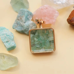 Detail of square gold-framed perfume pendant filled with green natural crushed stones