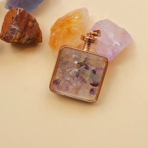 Macro shot of square rose gold perfume pendant filled with mixed natural crystal stones