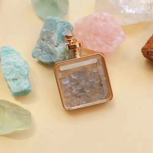 Macro detail of square gold pendant filled with natural grey crystal stone chips