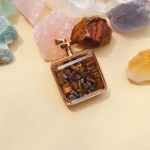 Macro view of square gold-framed pendant filled with natural tiger's eye stone chips