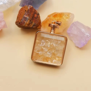 Detailed macro view of square crystal perfume bottle pendant with golden metal frame
