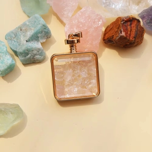 Macro view of square glass perfume pendant with gold metal frame and clear crystal gravels