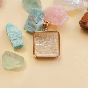 Detail of square gold perfume bottle pendant filled with clear quartz crystal stones