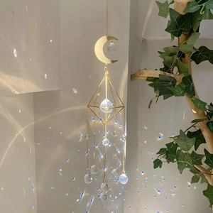 Golden moon suncatcher with K9 crystal creating rainbow light on a white wall