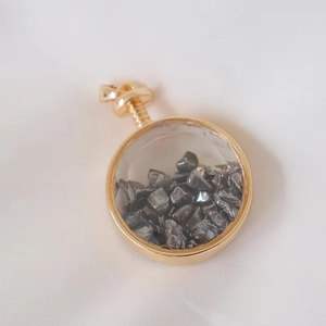 Macro shot of circular gold necklace pendant filled with natural dark gray crystal stones
