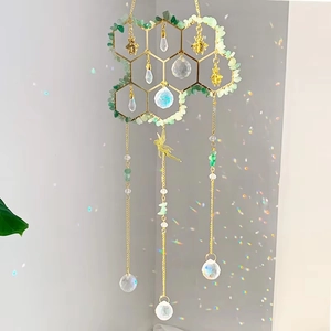 Detail of crystal suncatcher with golden honeycomb frame and emerald green stones