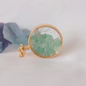 Close-up of golden round perfume pendant filled with natural green crystal stones