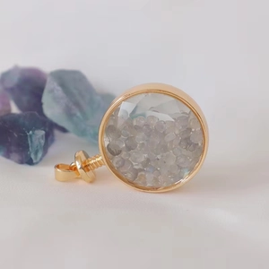 Macro detail of round gold pendant filled with gray labradorite crystal stone chips