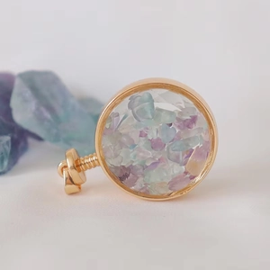 Detailed close-up of a gold round aromatherapy perfume pendant filled with natural crystals