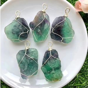 Vue détaillée de cinq pendentifs en fluorite brute faits main dans un plat en céramique