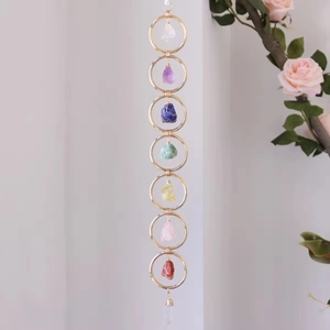 Close-up of handmade chakra wall hanging with raw crystals in gold metal rings