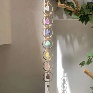 Detail of seven chakra crystal wall hanging with gold metal rings and raw stones