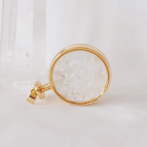 Macro shot of circular gold perfume pendant filled with natural clear crystal stones